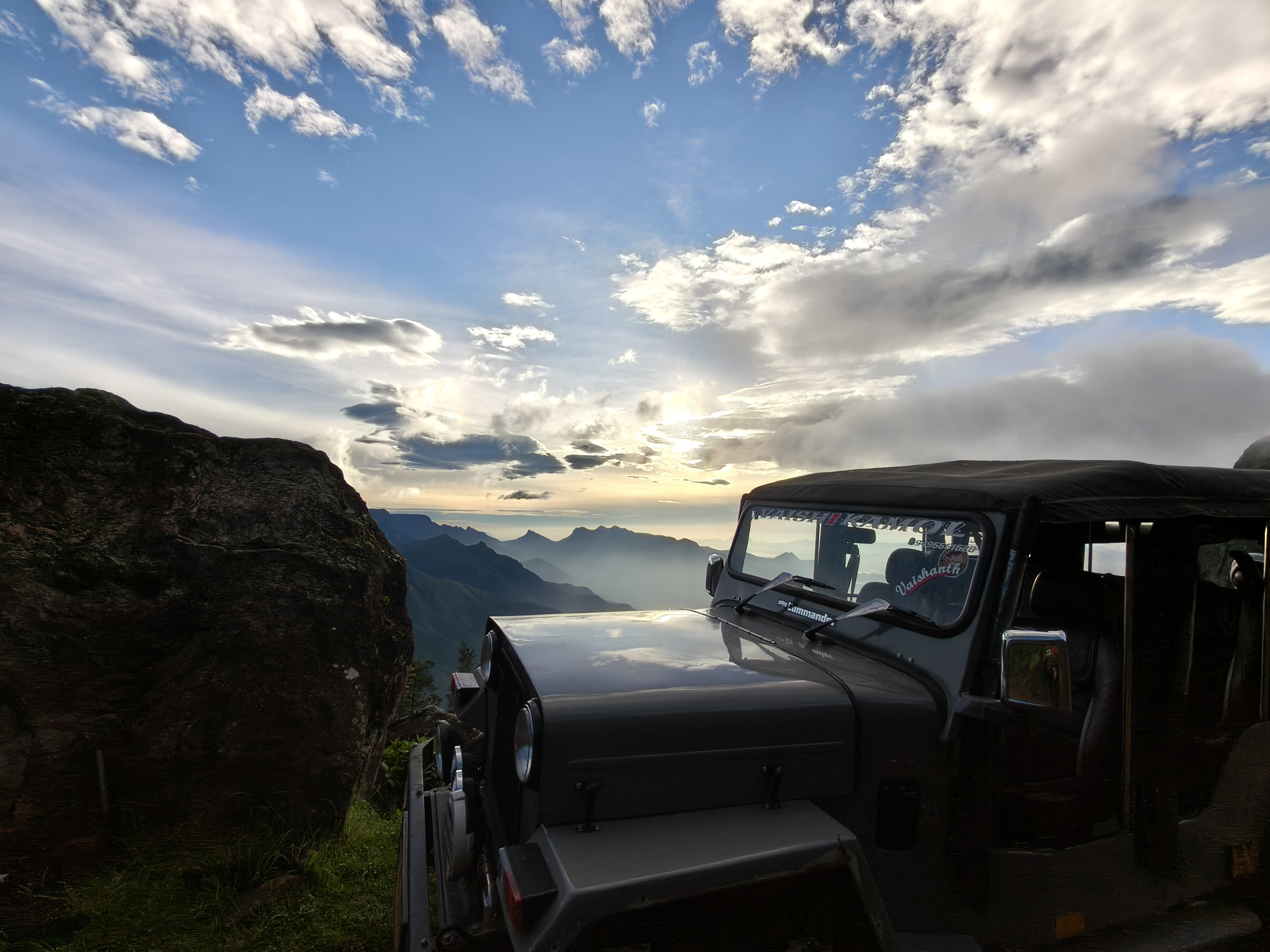 Kolukkumalai sunrise view with layered mountains, cloudy sky and glowing morning light
